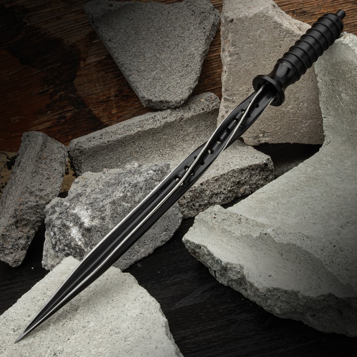 The Black Titanium Spiral Dagger laying on broken cinder blocks.